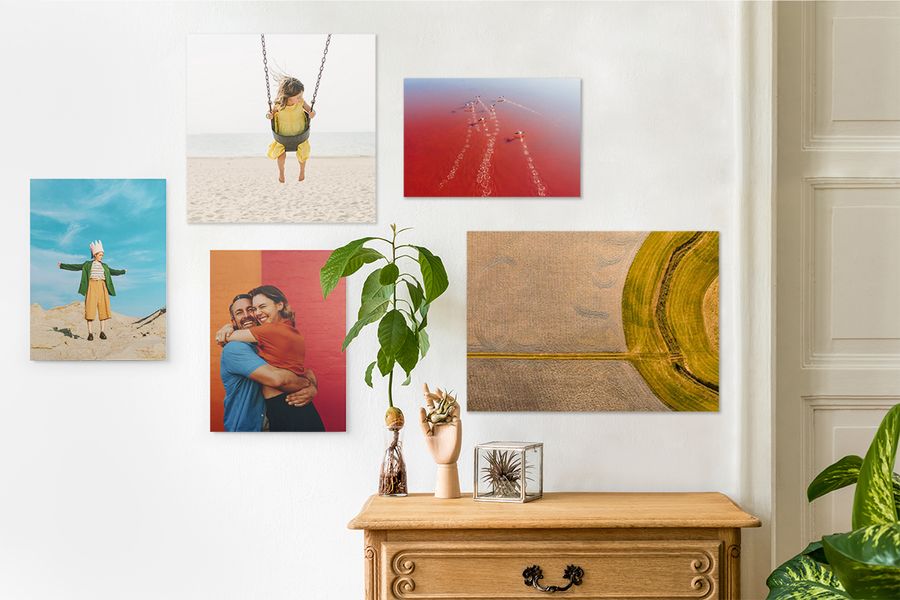 A lifestyle shot of a room with wall art of all materials on a wall, a table with plants and decorations, and other plants surrounding the wall art.