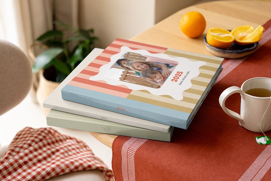 En stabel med fargerike, mønstrede fotoknudsen årbøker og årets fotobok med varierende design på et salongbord.