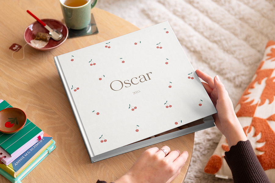 En kvinne som skal til å åpne mitt første år fotobok fra fotoknudsen på et salongbord i tre.