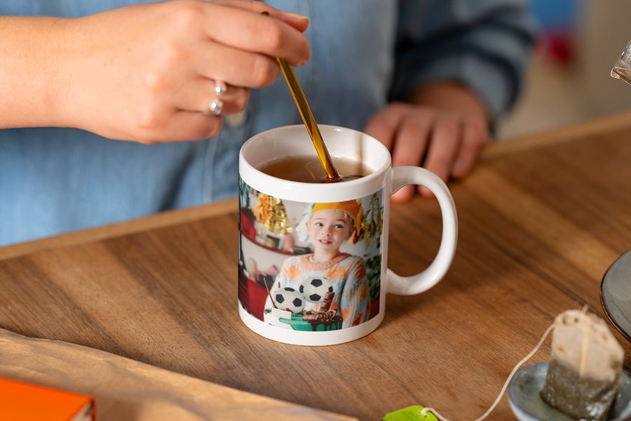 Et personlig krus fra fotoknudsen med en gutt og en fotballkake, som er en flott personlig bursdagsgave ved siden av en fotobok eller et fotoalbum på nett.