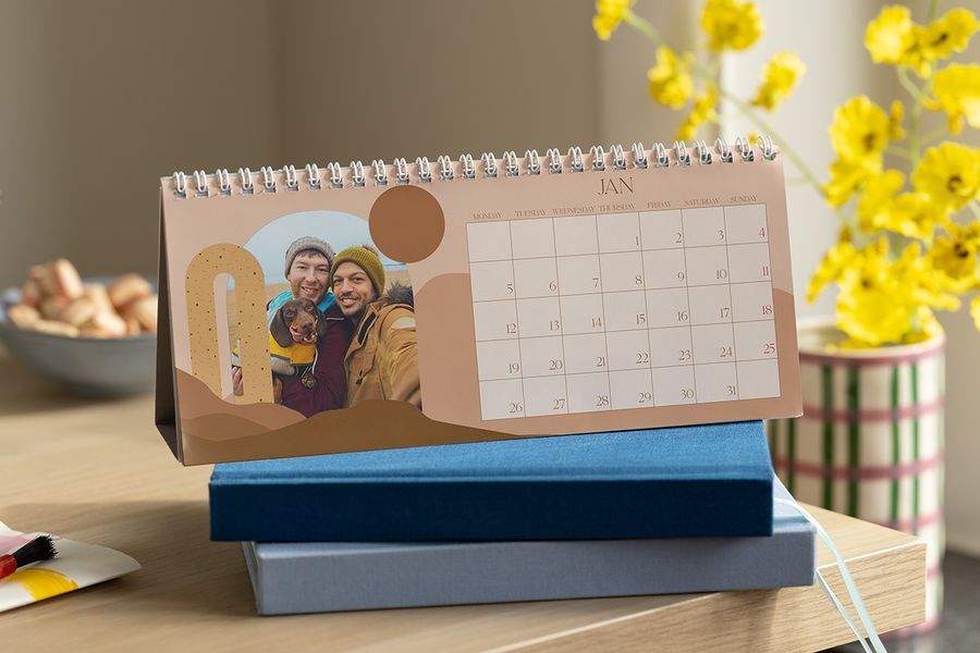 En personlig bordkalender med et bilde av to menn og en hund, som viser kreativ skrivebordsdekor hos fotoknudsen.