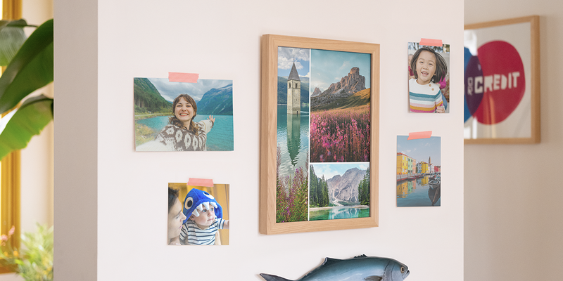 fotoknudsen fremkalle bilder vist på en vegg hjemme, med en stor ramme fylt med landskapsbilder og fire individuelle familiebilder festet på veggen, som inspirasjon til foto printing og å bestille bilder på nett.