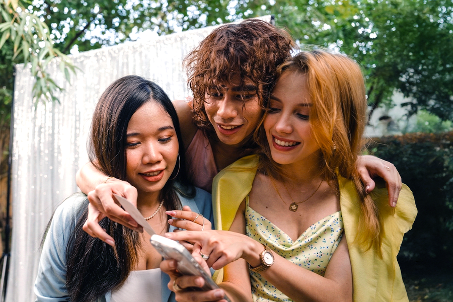 Tre venner i pent bryllupsantrekk deltar i en bryllupslek med fotoskattejakt, som inspirasjon til fotoknudsen bryllupsleker og morsomme bryllupsleker.