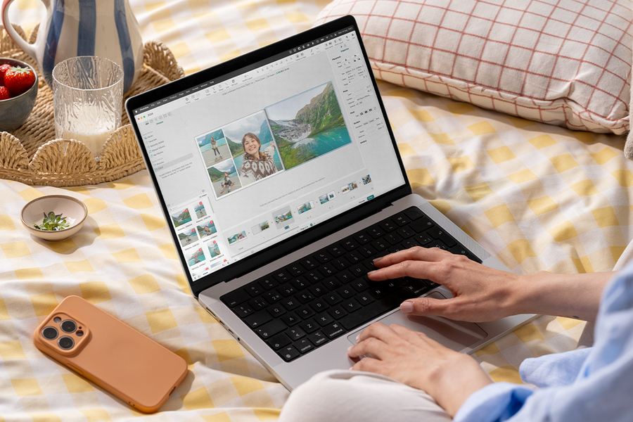 En person bruker fotoknudsen fotobok-editor på en bærbar datamaskin i sengen, som inspirasjon til en enkel fotobok og en fotoalbum maker.