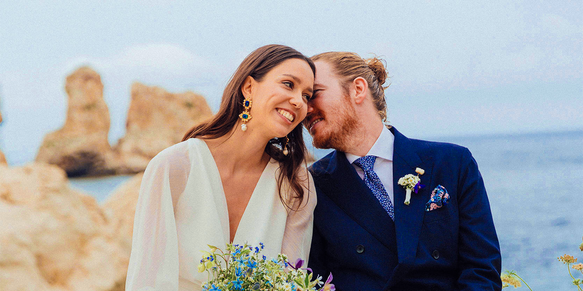 Et smilende brudepar på stranden på bryllupsdagen, som inspirasjon til fotoknudsen bryllupsleker og morsomme bryllupsleker.