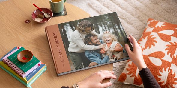 En fotoknudsen coffee table photo book med årsbilde og et fint familiefoto på forsiden, plassert på et stuebord som inspirasjon til en personlig coffee table book.