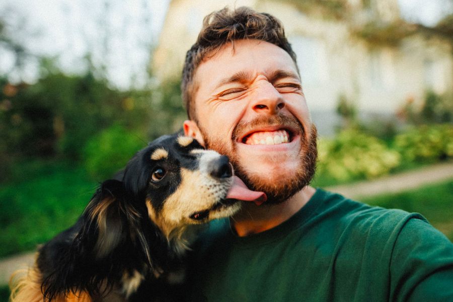 En mann smiler sammen med hunden sin, som inspirasjon til et farsdagskort fra hunden og morsom tekst til farsdagskort for hundepappaer.