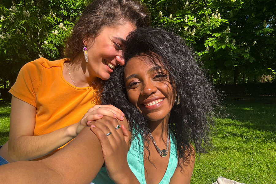 To kvinner smiler og tar en selfie i en frodig grønn park, og illustrerer hvordan sterke farger kan gjøre bilder i sollys mer levende og fulle av liv.