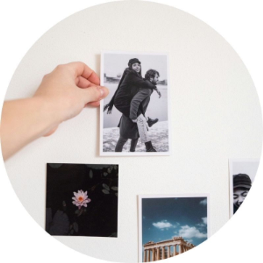 En hånd holder et bilde av et par ved siden av andre bildeutskrifter, som illustrerer Andreas frierihistorie og en meningsfull frieriidé full av minner fra fotoknudsen.