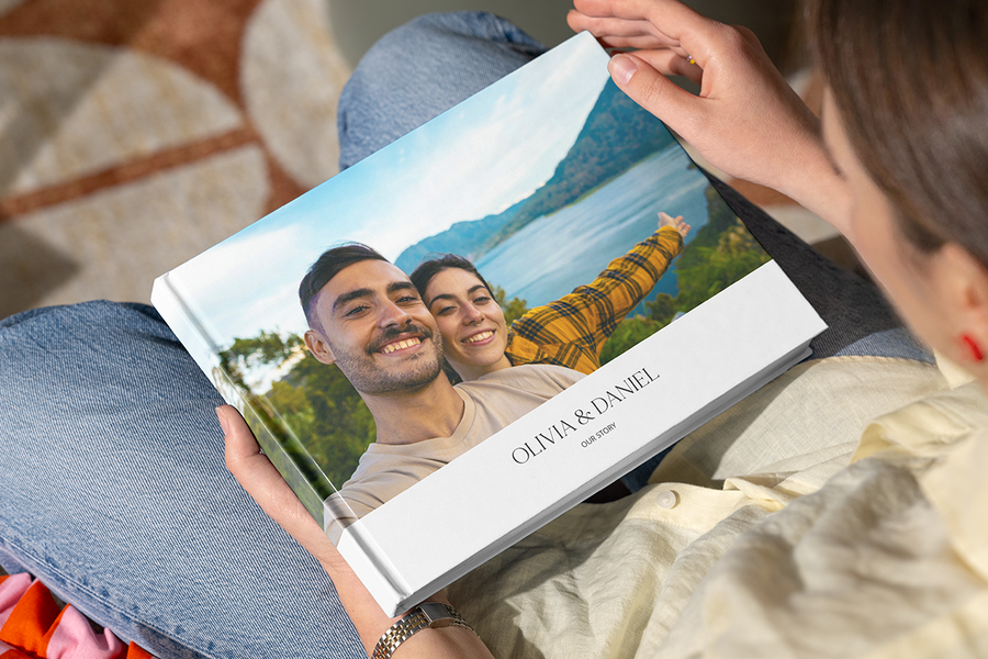 En personlig fotoknudsen fotobok med et lykkelig par på et vakkert sted på forsiden, som illustrerer en fotobokoverraskelse som en romantisk frieriidé.