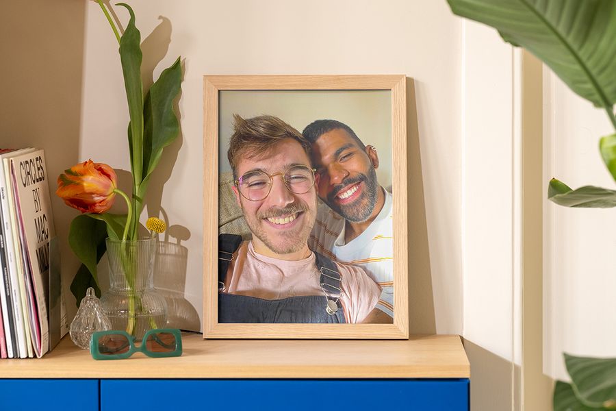 Et innrammet bilde av to menn som tar en selfie i solen står på en skjenk ved siden av en vase, solbriller og et magasin, som inspirasjon til sommerlig interiør hjemme.