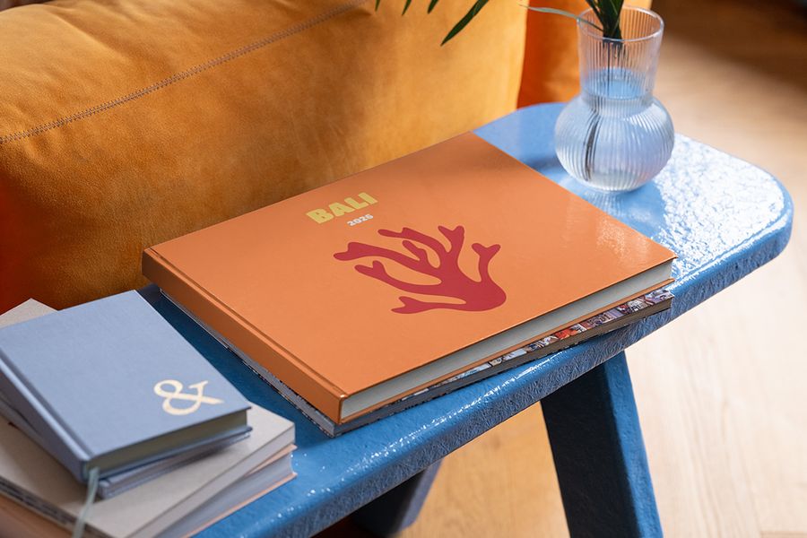 En personlig fotoknudsen reisefotobok i liggende format om Bali ligger på et blått sofabord, som inspirasjon til sommerlig styling av små flater hjemme.
