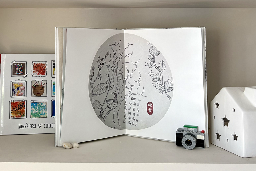 En åpen barnefotobok viser et fullsides oppslag med tresketser og tekst, ved siden av en lukket fotobok med et scrapbook-inspirert omslag med ulike eksempler på barnekunst, som illustrerer det meningsfulle minnet en fotoknudsen barnefotobok skaper.