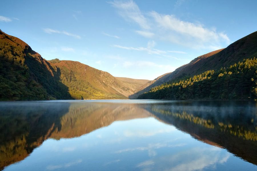 Lyngdekte skråninger og den berømte Lough Tay, kjent som «Guinness-sjøen», i Wicklow Mountains nasjonalpark i Irland, en av Europas legendariske naturparker i fotoknudsen sin guide.