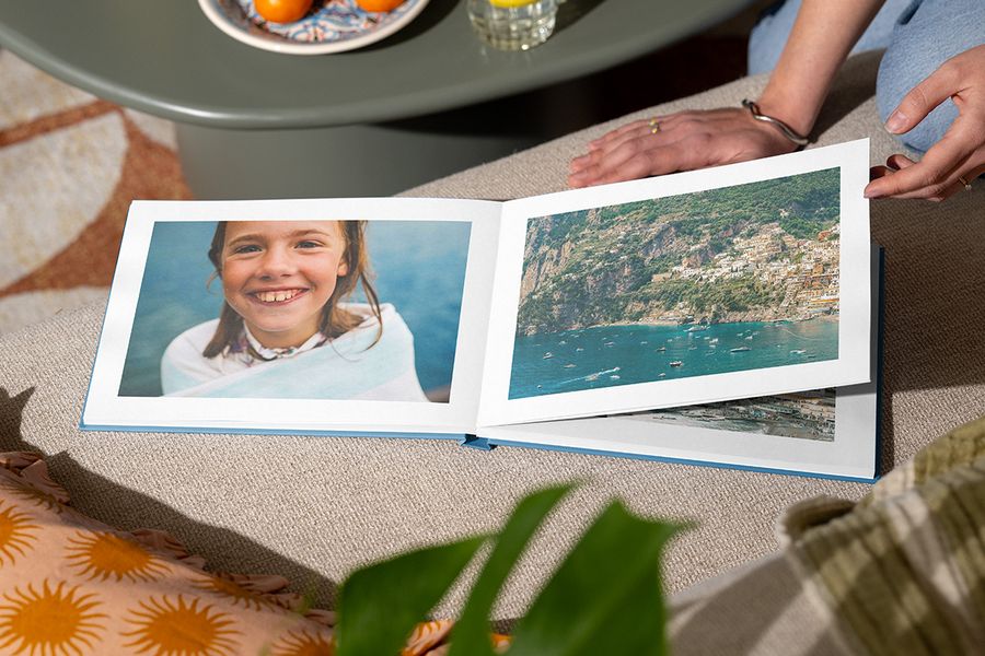 En åpen fotobok viser en jente som smiler ved havet på én side og et strandlandskap på den andre, som illustrerer fotoknudsen sitt Holiday Escape-design med fengslende fullsidefotografier.