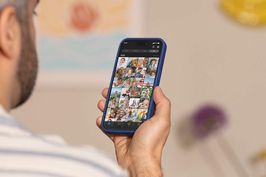 En mann holder telefonen sin og blar gjennom kamerullen, som illustrerer fotoknudsen sin guide til de beste verktøyene for å organisere bilder.