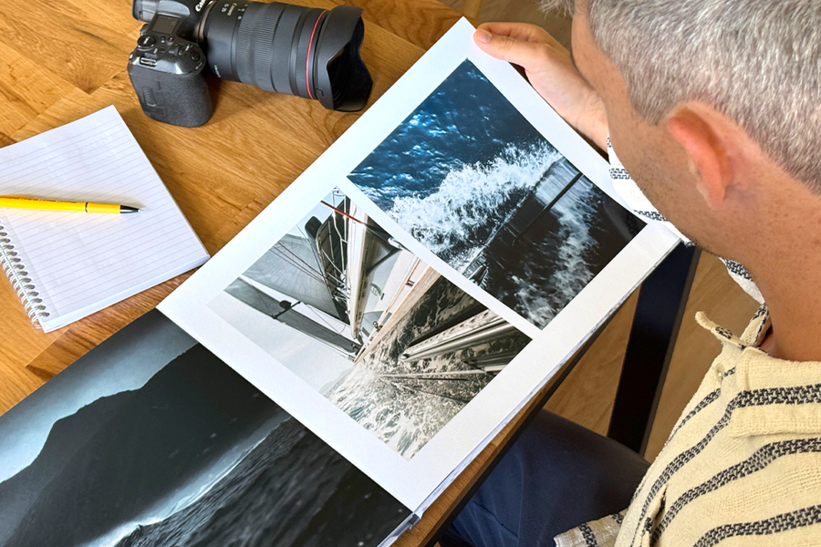 Fotograf Charl van Rooy ser ned på porteføljen sin, med kameraet og en notatbok på bordet ved siden av seg, som illustrerer fotoknudsen sine tips til å velge de beste malene og layoutene for en fotografiportefølje.
