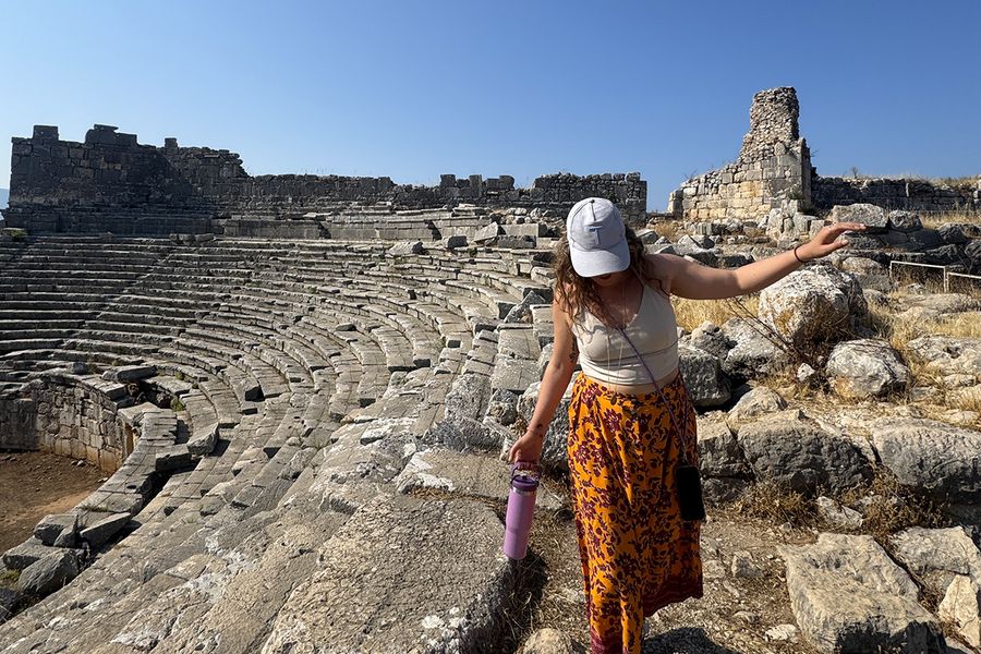 Gemma, tekstforfatter hos fotoknudsen, går blant steinene ved et amfiteater i Kalkan, Tyrkia, som illustrerer hvordan man velger det riktige septemberreisemålet for ferien.