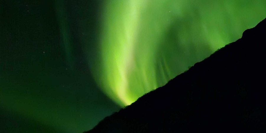 Nordlys på himmelen i veldig grønne farger, som illustrerer fotoknudsen sine tips for å fotografere nordlys.