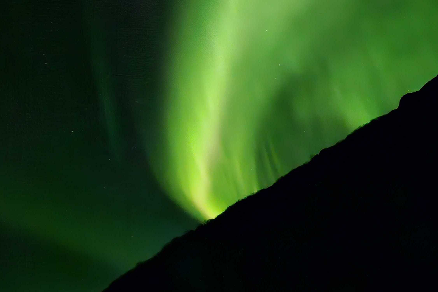 Nordlys på himmelen i veldig grønne farger, som illustrerer fotoknudsen sine komposisjonstips for fotografering av nordlys.