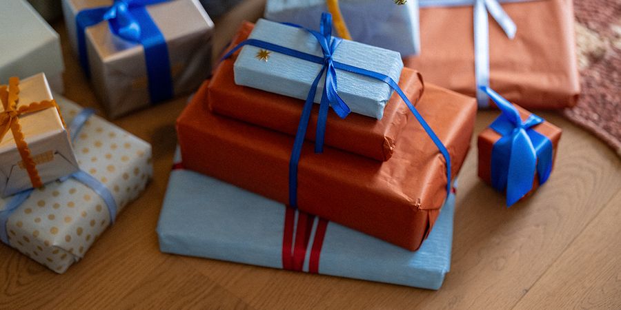 En stabel innpakkede gaver med blå bånd på et tregulv, til illustrasjon av fotoknudsen sine tips for black friday julegaver.