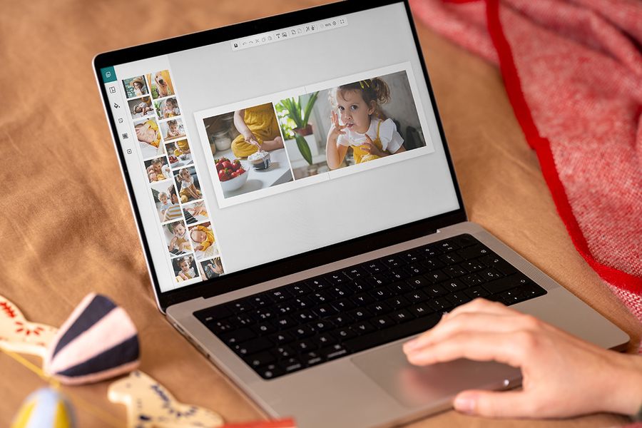 Hender ved en bærbar PC som viser fotoknudsens nettbaserte designprogram, for å vise hvor enkelt det er å lage en fotobok som personlig julegave, som illustrerer fotoknudsen sin tidslinje for å lage en personlig fotogave.