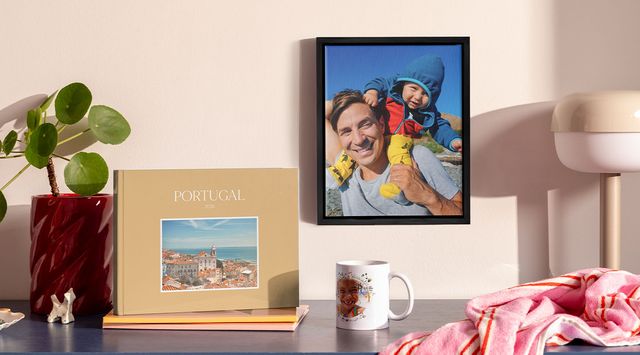 En samling av personlige fotoprodukter utstilt på en hylle, inkludert en fotobok, innrammet trykk og kopp med bilde.