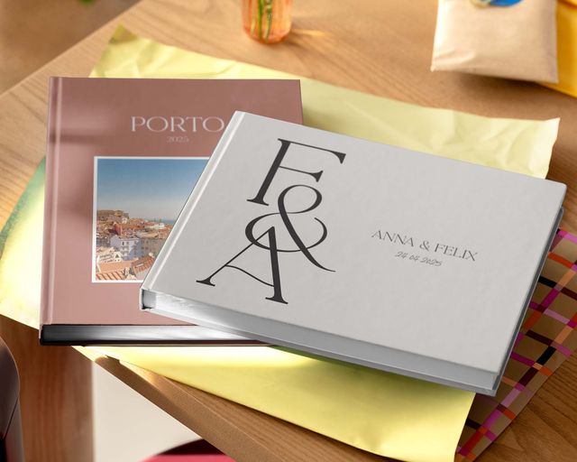 To personlige fotobøker som vises på et bord i forskjellige størrelser og design.