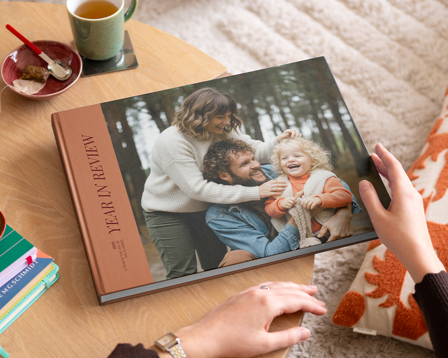 En fotoknudsen coffee table photo book med årsbilde og et fint familiefoto på forsiden, plassert på et stuebord som inspirasjon til en personlig coffee table book.