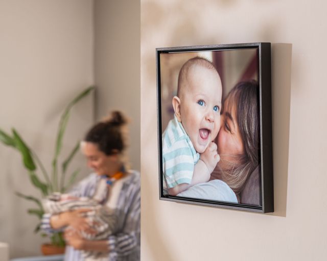 Innrammet lerretsbilde av en mor som klemmer babyen sin, på en vegg