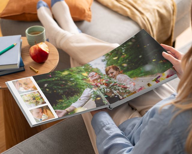 Kvinne ser på en åpen fotobok med bryllupsbilder i layflat-innbinding.