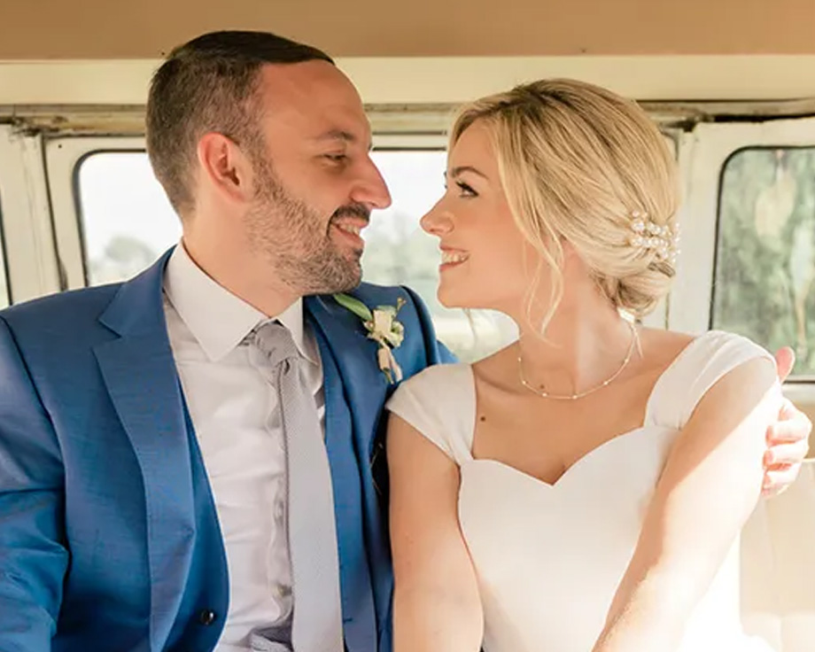 Fee, spesialist på redaksjonelt innhold hos fotoknudsen, og ektemannen hennes smilende i bryllupsbilen sin, som illustrerer en personlig historie om tips til bryllupsplanlegging.