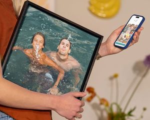 En kvinne holder fotoknudsen veggdekor med et motiv av en familie som leker i vannet på ferie, som inspirasjon til å gjøre feriebilder om til flott veggkunst.